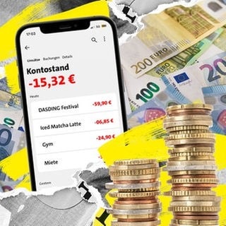 Ein Smartphone mit einer Banking-App, die einen Kontostand im Minus anzeigt. Daneben Münzen und Euroscheine.