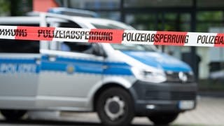 Ein Polizeiauto steht hinter einer Absperrung 