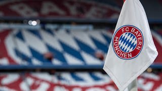 Eine Eckfahne mit dem Logo vom FC Bayern München ist vor dem Spiel vor den leeren Rängen zu sehen