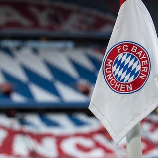 Eine Eckfahne mit dem Logo vom FC Bayern München ist vor dem Spiel vor den leeren Rängen zu sehen