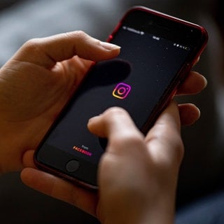 Auf dem Bildschirm eines Smartphones sieht man das Logo der App Instagram.