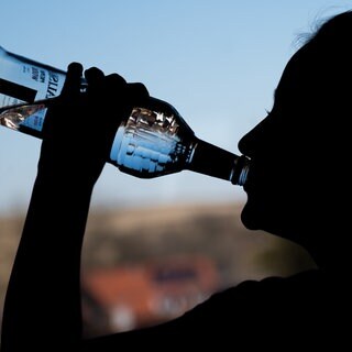 Ein Mädchen trinkt in ihrem Zimmer eine Flasche Wodka.