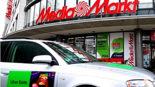 Ein Auto mit Uber-Aufdruck steht vor einer MediaMarkt-Filiale