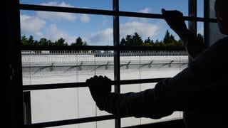 Ein Häftling stehtim Neubau der Justizvollzugsanstalt an einem vergitterten Fenster in einer Zelle.