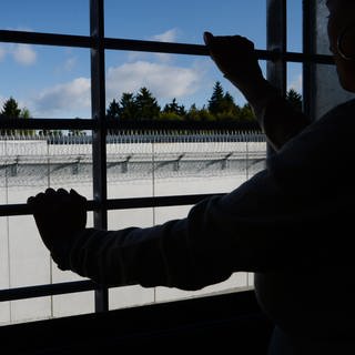 Ein Häftling stehtim Neubau der Justizvollzugsanstalt an einem vergitterten Fenster in einer Zelle.