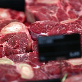 Rinderbeinscheiben liegen in einem Supermarkt hinter Preisschildern in der Auslage der Fleisch-Theke.
