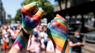 Zwei Teilnehmer der «Pride Berlin: Save our Community, Save our Pride» halten ihre Faust in die Höhe, die in Regenbogenfarbe angemalt sind.