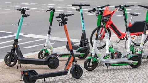 E-Scooter zum Leihen von verschiedenen Anbietern stehen an einer Straßenkreuzung.