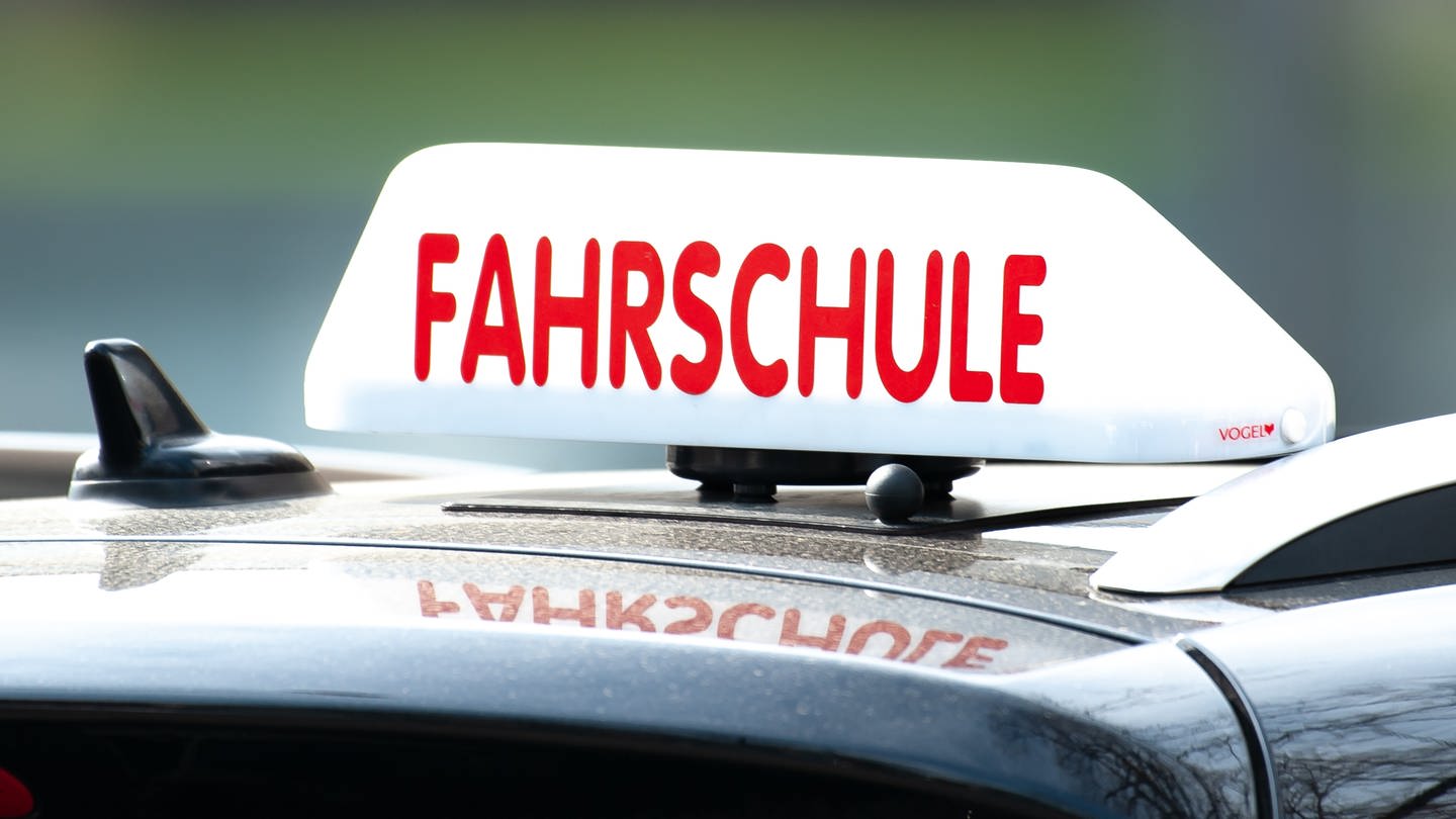 Ein Schild mit der Aufschrift «Fahrschule» ist auf einem Fahrschulauto befestigt.