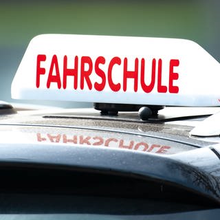 Ein Schild mit der Aufschrift «Fahrschule» ist auf einem Fahrschulauto befestigt. 