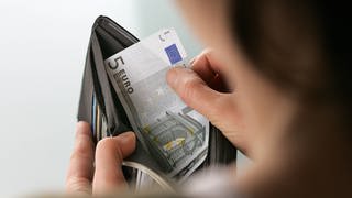 Eine Frau nimmt Geldscheine aus einem Portemonaie