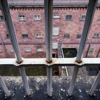Durch ein Fenstergitter in einem Gebäude des ehemaligen Gefängnisses „Fauler Pelz“ (Gefängnis Heidelberg) ist ein Innenhof zu sehen.
