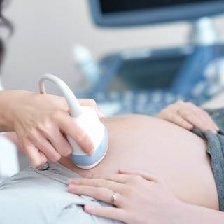 Doctor using ultrasound equipment screening of pregnant woman.