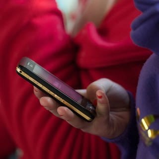 Eine Schülerin hält ein mobiles Telefon in der Hand. Bei Kinderporngrafie ermittelt die Polizei immer öfter auch gegen Minderjährige.