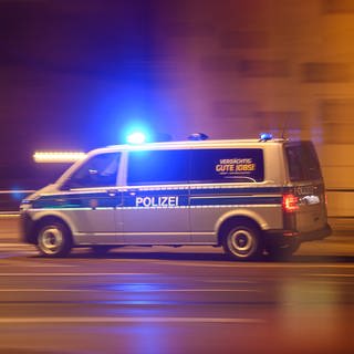 Ein Polizeiwagen mit Blaulicht fährt am Silvesterabend durch die Innenstadt zu einem Einsatz (Symbolbild)