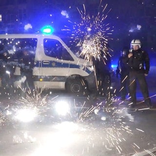 Polizeibeamte stehen hinter explodierendem Feuerwerk. Nach Angriffen auf Einsatzkräfte in der Silvesternacht hat die Diskussion um Konsequenzen begonnen.