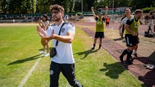 Fußball, Berlin-Pokal, Delay Sports Berlin - 1. Traber FC Mariendorf: Elias Nerlich, FIFA-Streamer, steht am Spielfeldrand und klatscht.