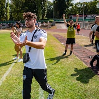 Fußball, Berlin-Pokal, Delay Sports Berlin - 1. Traber FC Mariendorf: Elias Nerlich, FIFA-Streamer, steht am Spielfeldrand und klatscht.