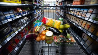 Verschiedene Lebensmittel liegen in einem Supermarkt in einem Einkaufswagen. Immer mehr Deutsche müssen sich beim Essen einschränken.