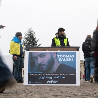 Ein großes Plakat steht bei einer Protestaktion gegen das Iran-Regime auf dem Pariser Platz. Es zeigt den iranischen Rapper Toomaj Salehi.