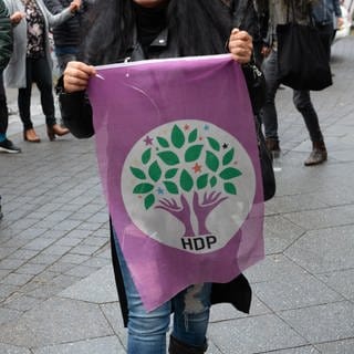 Eine Frau geht mit einer Fahne der kurdischen Partei HDP in Kreuzberg über einen Weg.