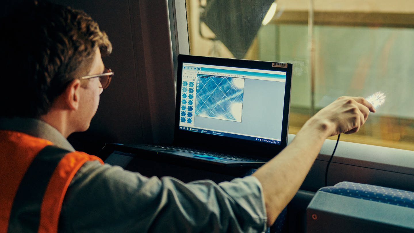 Ein Mitarbeiter der Deutschen Bahn lasert eine Scheibe, um den Mobilfunk im Zug zu verbessern.