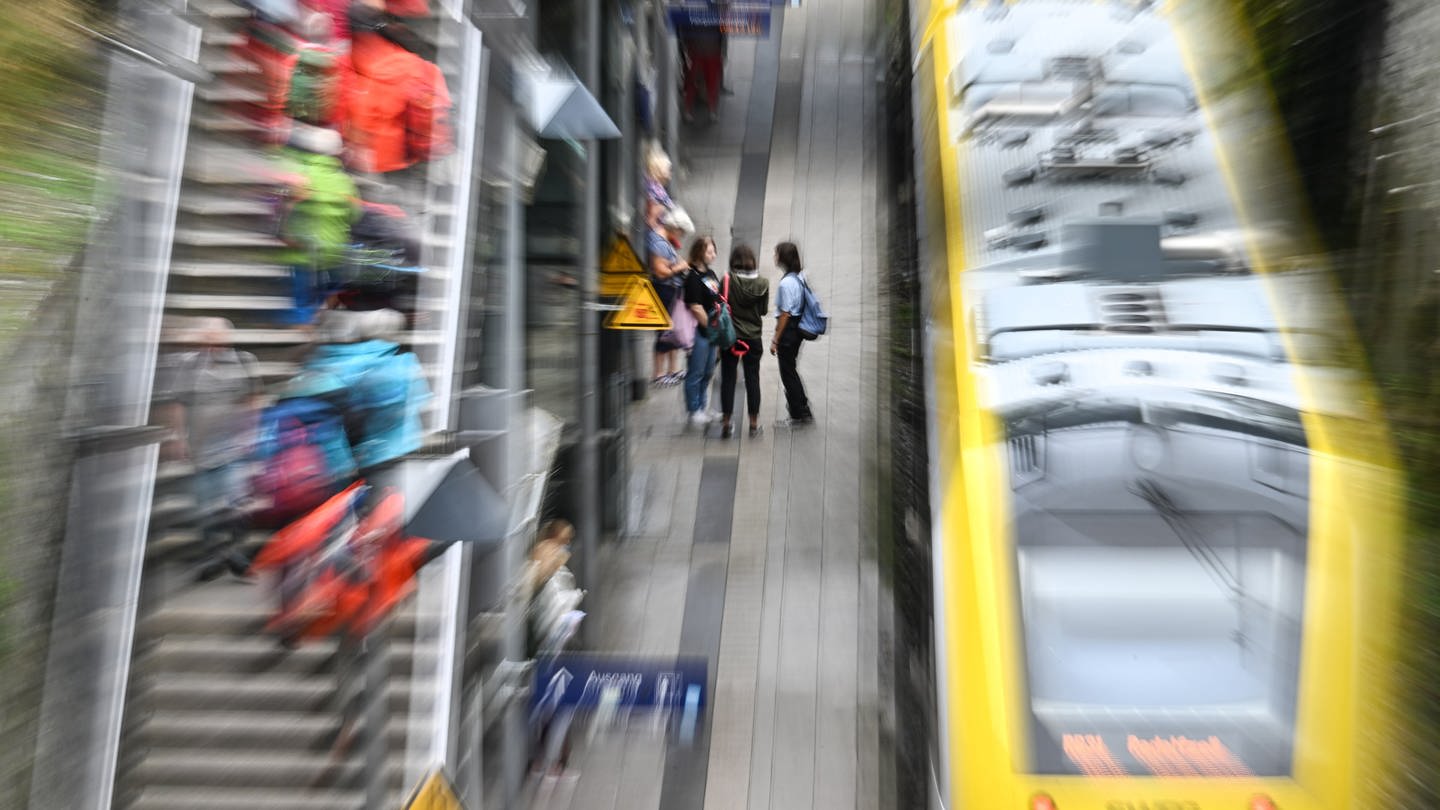 Zugreisende stehen am Bahnhof, um in einen Zug einzusteigen. Die Regierung von Baden-Württemberg hat angekündigt, dass Pendeln in Zukunft besser klappen soll.