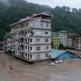 Gebäude sind vom Hochwasser nach einer Sturzflut umgeben. In der Nacht auf Mittwoch, 04.10.2023, hat Starkregen unter anderem den Wasserpegel des Flusses Teesta stark ansteigen lassen. Unter Berufung auf Behördenangaben sollen mindestens 14 Menschen ums Leben gekommen sein und mehr als 100 Menschen werden vermisst.