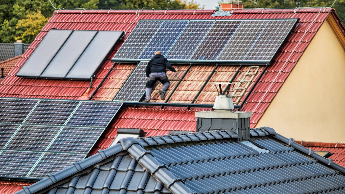 Ein Mann montiert eine Solaranlage auf einem Dach