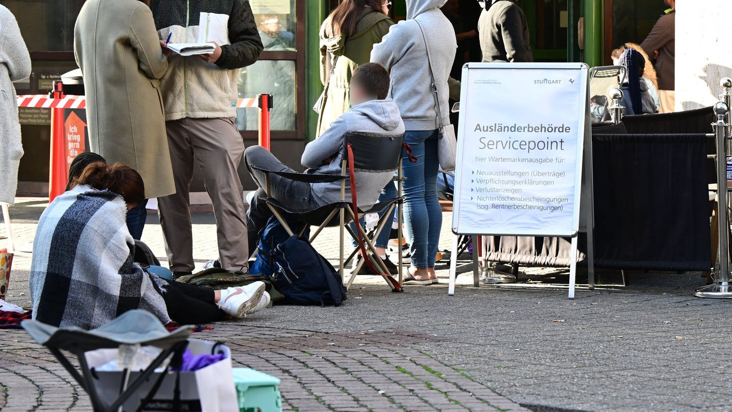 Menschen warten schon Stunden vor der Öffnung vor dem Eingang der Stuttgarter Ausländerbehörde. Die Wartezeiten sind in den letzten Monaten drastisch angestiegen.