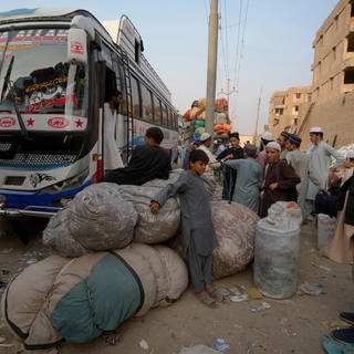 Afghanische Familien warten darauf, in Busse einzusteigen, die sie in ihr Heimatland bringen sollen. UN-Organisationen berichten von einem starken Anstieg der Zahl der Afghanen, die in ihre Heimat zurückkehren, seit Pakistan ein hartes Durchgreifen gegen illegal im Land lebende Menschen eingeleitet hat.