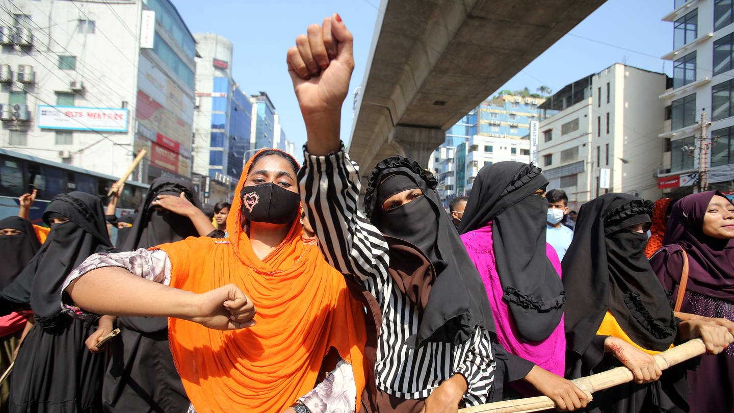 Bei einer Demonstration von Textilarbeitern und Arbeiterinnen reckt eine Frau ihre Faust in die Luft. In Bangladesch haben Tausende Beschäftigte der Textilbranche für eine bessere Bezahlung ihrer Arbeit protestiert. Es kam zu Zusammenstößen mit der Polizei.