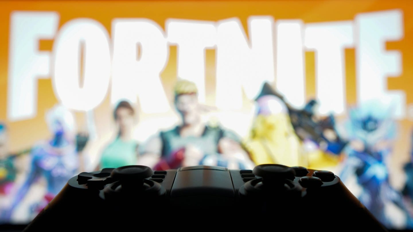 Spielkonsole und Fortnite-Screen im Hintergrund: Die neue Season Fortnite OG ist online - es ist eine Reise zu den Anfängen des Games.