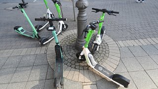 E-Scooter verschiedener Anbieter stehen auf dem Gehweg. - In Mainz soll es jetzt Parkzonen für die Leih-Roller geben