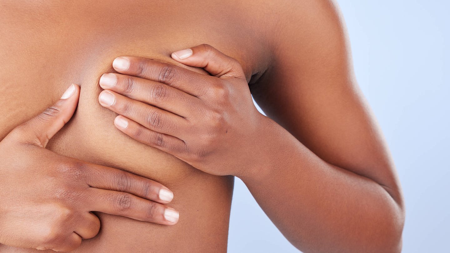 Eine Frau tastet ihre Brust nach Knoten ab. Etwa 290 000 Frauen in Großbritannien könnten künftig vorbeugend ein Medikament gegen Brustkrebs nehmen.
