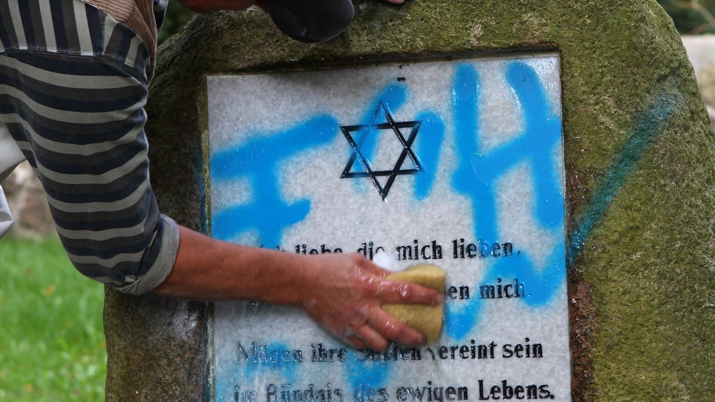 Ein Mitarbeiter eines Steinmetzbetriebes beseitigt Schmierereien am Gedenkstein auf dem jüdischen Friedhof. (Symbolbild Antisemitismus)