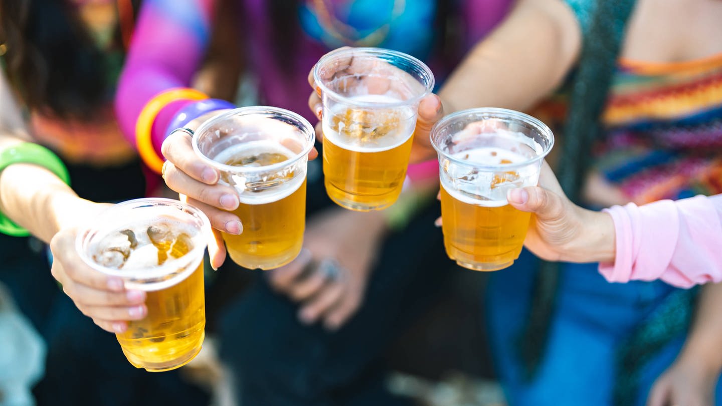 Junge Menschen mit Plastik-Bierbechern stoßen an. Alkoholkonsum und Alkoholvergiftungen bei Jugendlichen geht weiter zurück.