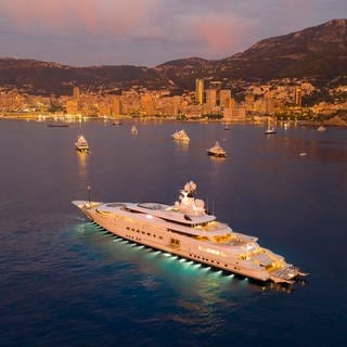 Eine Luxusyacht vor Anker kurz vor Sonnenaufgang vor dem Fürstentum Monaco.