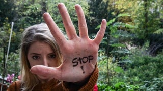 Eine Frau streckt ihre Hand, auf dem das Wort "Stop" steht, in Abwehrhaltung in die Kamera. Am Orange-Day setzen sich Menschen dafür ein, dass Frauen nicht mehr unter Gewalt leiden müssen