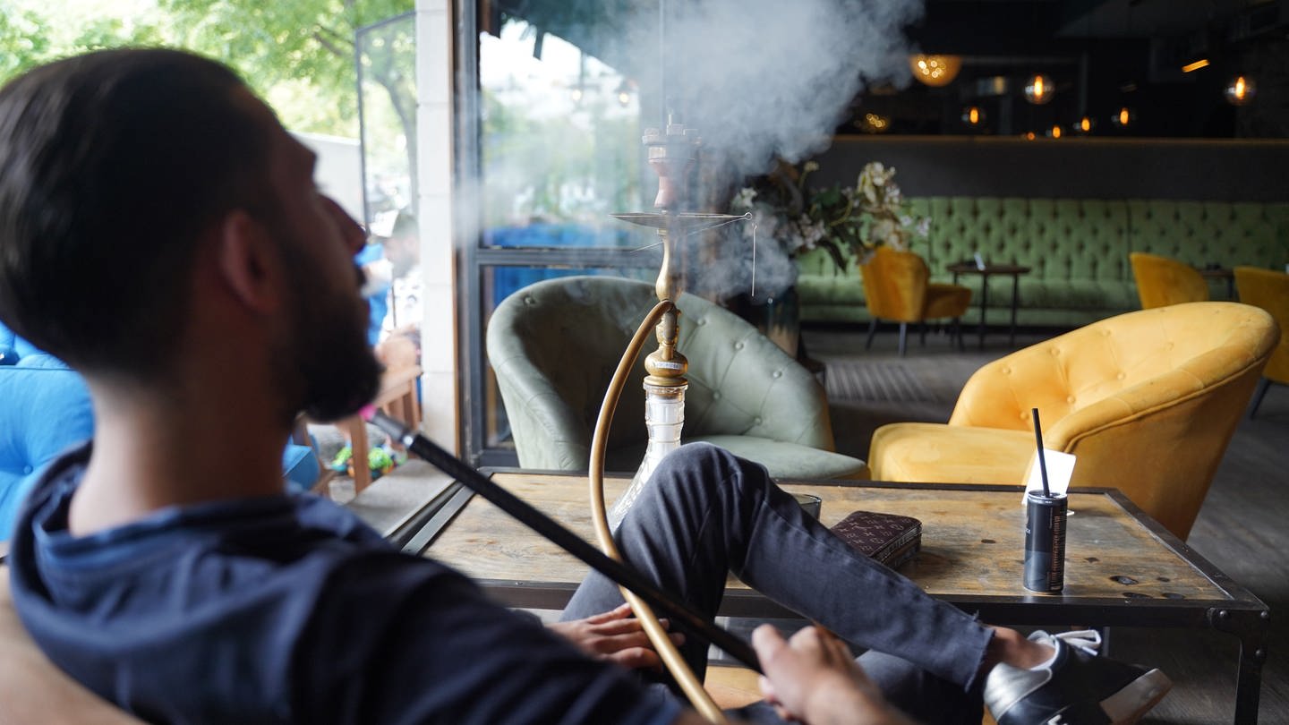 Ein junger Mann raucht eine Shisha in einer Shisha-Bar.