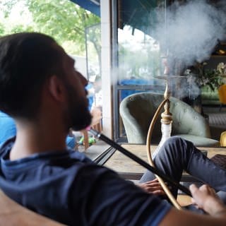 Ein junger Mann raucht eine Shisha in einer Shisha-Bar.