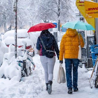 Zwei Menschen laufen mit Regenschirmen durch den tiefen Schnee in der Stadt. Der Schneefall ist aber kein Zeichen gegen den Klimawandel. 