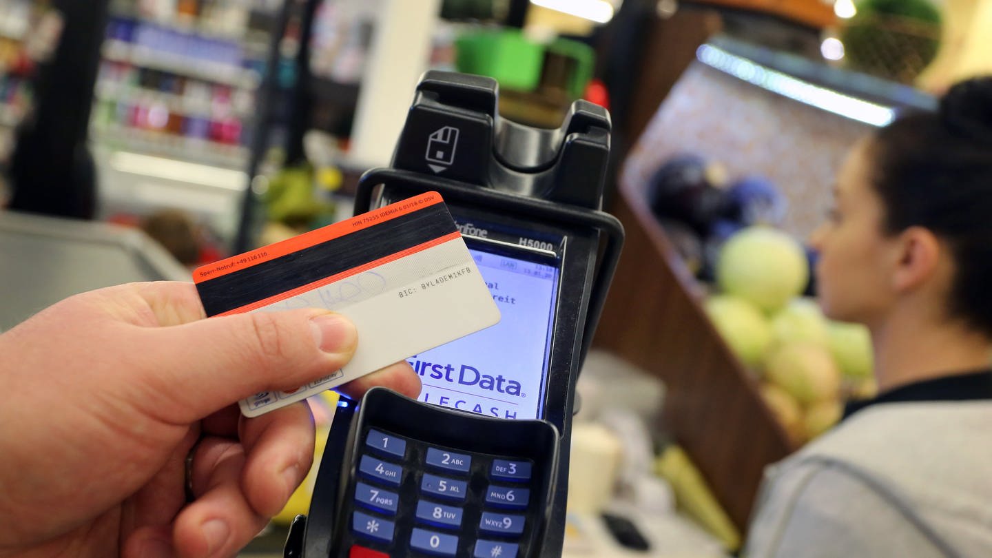 Eine EC-Karte wird an den Bezahl-Terminal an der Kasse eines Supermarktes gehalten.