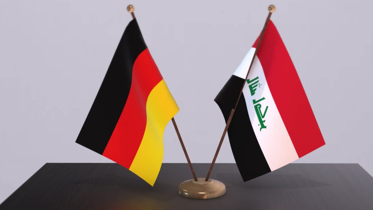 Die Flaggen von Deutschland und dem Irak stejem auf einem Tisch. Angeblich gibt es einen geheimen Deal zwischen beiden Ländern. Es geht unter anderem um Abschiebungen.