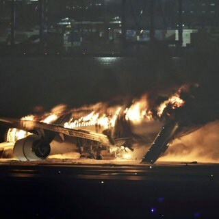 Ein Flugzeug der Japan Airlines brennt auf der Landebahn des Tokioter Flughafens Haneda. Ein Passagierflugzeug ist bei der Landung auf dem Tokioter Flughafen Haneda in Brand geraten. Auf Live-Bildern des japanischen Fernsehsenders TBS war am Dienstagabend (Ortszeit) zu sehen, wie Passagiere während der Löscharbeiten die Maschine über eine Notrutsche verließen