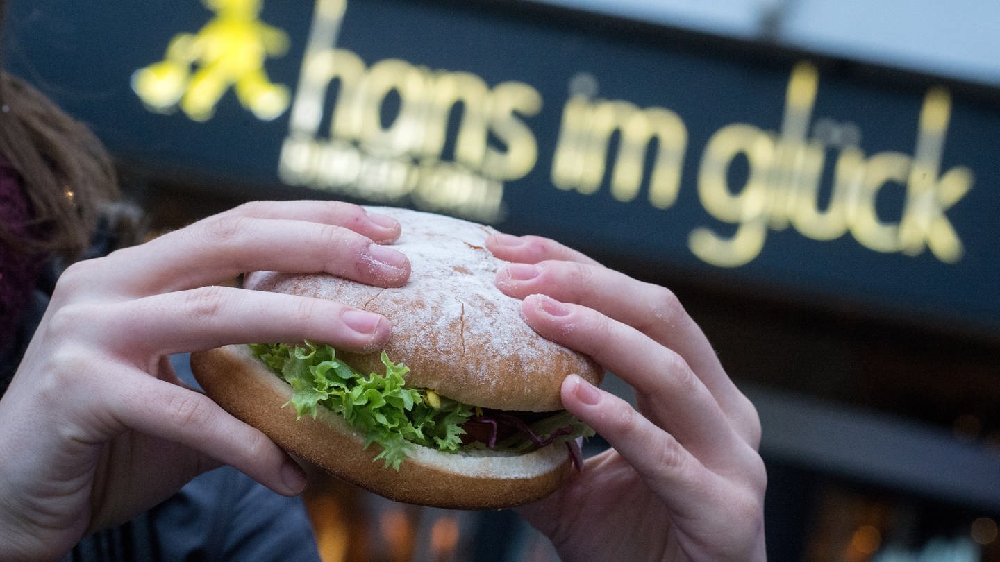 Eine junge Frau hält einen Burger der Burger-Kette 