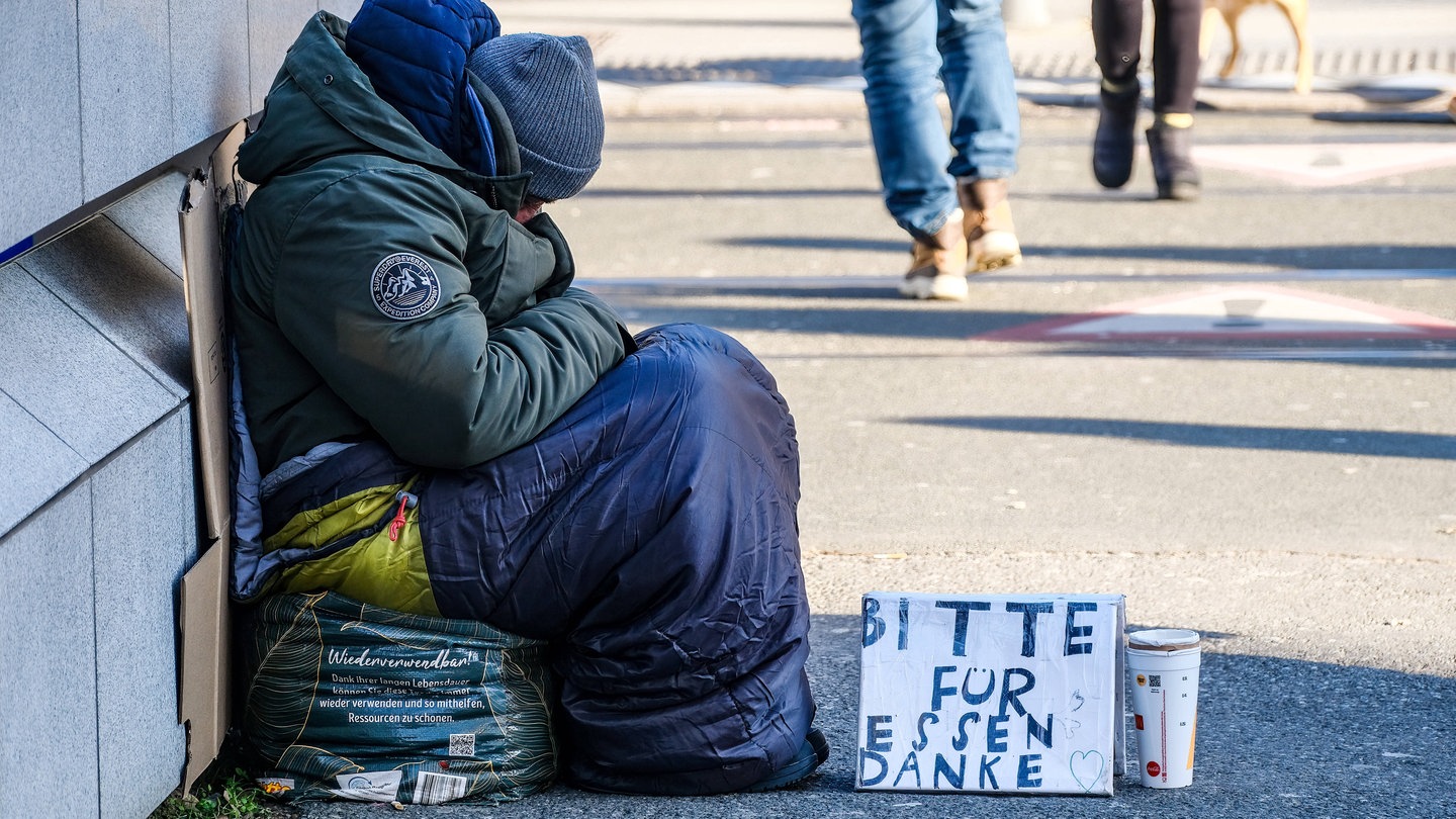 Ein Obdachloser sitzt auf der Straße und bittet um Spenden für Essen. Eine neue Studie von Oxfam zeigt: Reiche werden immer reicher, Arme immer ärmer.