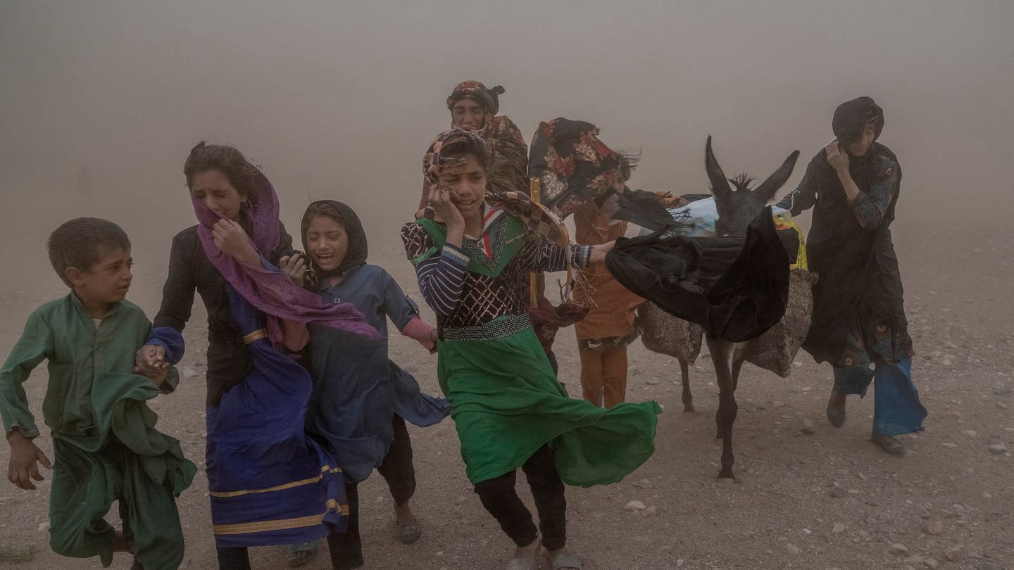 Afghanische Mädchen und Frauen tragen nach einem Erdbeben gespendete Hilfsgüter zu ihren Zelten.