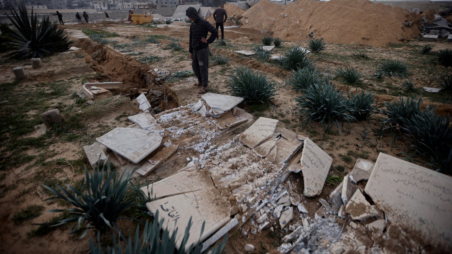 Palästinenser inspizieren beschädigte Gräber nach einem israelischen Panzerangriff auf einen Friedhof im Flüchtlingslager Chan Junis im südlichen Gazastreifen. (Symbolbild)