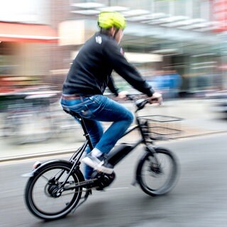 Ein Radfahrer fährt mit einem E-BikePedelec auf einer Fahrradstraße.